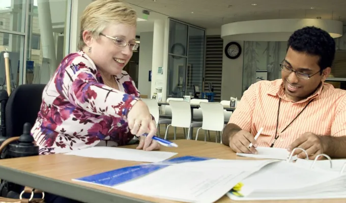 Two employees in wheelchairs conferring at a table