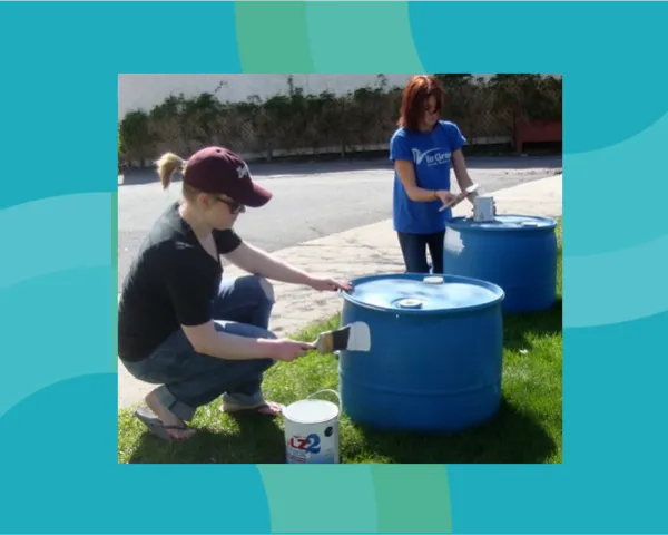 Two women painting barrels.