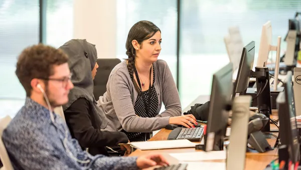 Photo of three office employees working in front of monitors on one table. Photo by Arlington Research on Unsplash.