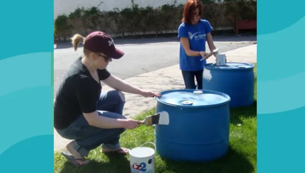 Two women painting barrels.